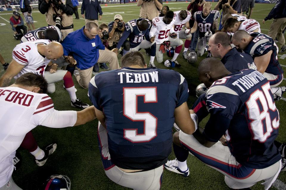 New England Patriots quarterback Tim Tebow prays with his teammates and members of the New York Giants after their NFL preseason game in Foxborough