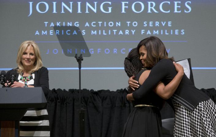 First lady Michelle Obama, right, hugs Chrissandra Jackson, center, accompanied by Dr. Jill Biden, left, at the third anniversary of Joining Forces, Wednesday, April 30, 2014, at the American Red Cross Hall of Service in Washington. Mrs. Obama announced pledges in excess of $150 million from foundations and corporations to help veterans and their families get the services they need in the places where they live as the country adjusts to a postwar footing. Jackson is a daughter of a military family. (AP Photo)