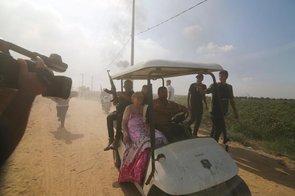 An elderly woman captured by Hamas is seen being driven down a road.