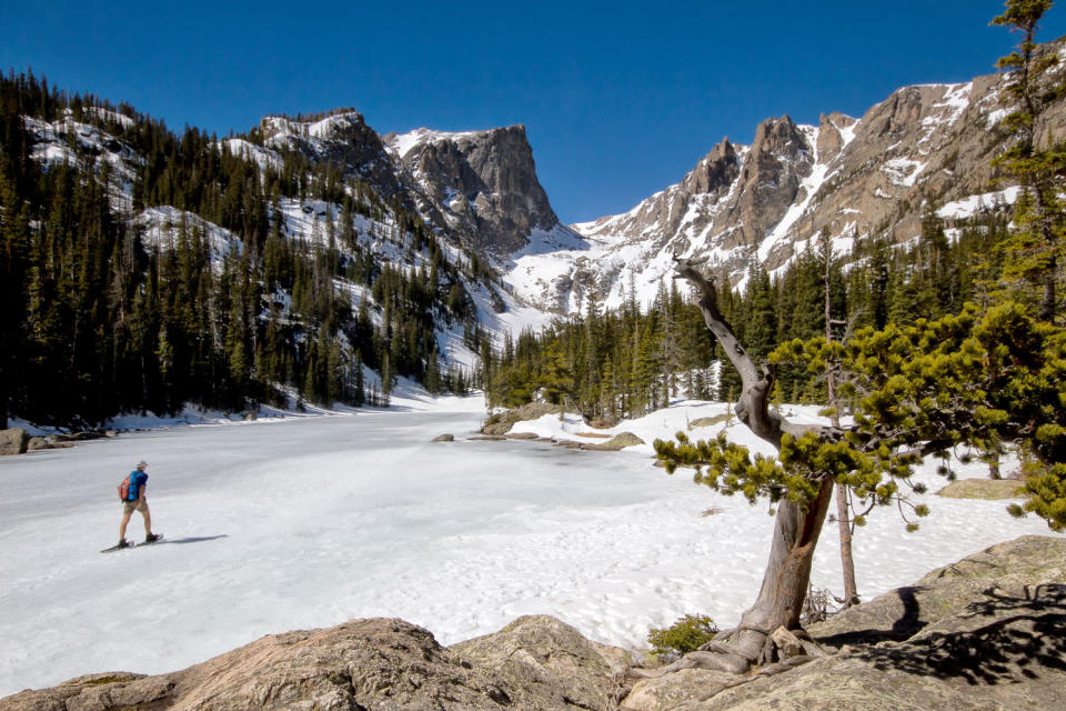 A snowshoer crosses Dream Lake on the Emerald Lake Trail in Rocky Mountain National Park. Hallet Peak sits in the background.