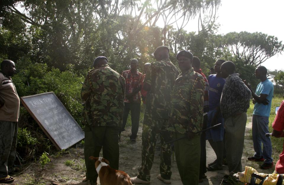 Policemen read a message written on a blackboard after an attack in Hindi village, near Lamu