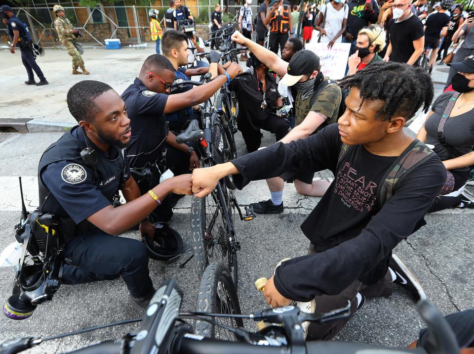 FILE - In this June 3, 2020, file photo, Atlanta Police Officer J. Coleman, left, and protester Elijah Raffington, of Sandy Springs, fist bump in a symbolic gesture of solidarity outside the CNN Center at Olympic Park, in Atlanta. George Floyd, a black man, died after being restrained by Minneapolis police officers on May 25 and his death sparked protests. Black officers find themselves torn between two worlds when it comes to the protests against police brutality happening around the U.S. (Curtis Compton/Atlanta Journal-Constitution via AP, File)