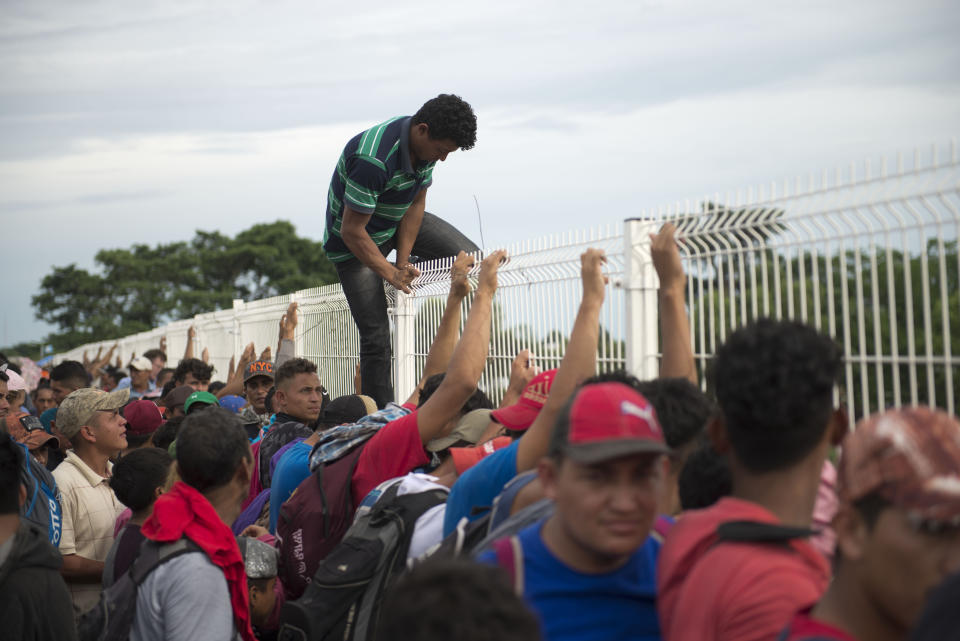 A migrant tired of waiting to cross into Mexico, climbs a border bridge fence to jump into the Suchiate River, in Tecun Uman, Guatemala, Friday, Oct. 19, 2018. Some of the migrants traveling in a mass caravan towards the U.S.-Mexico border organized a rope brigade to ford its muddy waters. (AP Photo/Oliver de Ros)