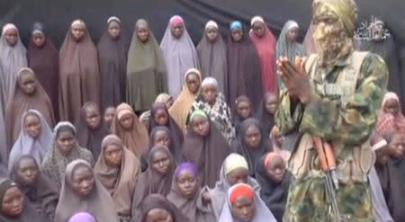 FILE PHOTO - A still image from a video posted by Nigerian Islamist militant group Boko Haram on social media, seen by Reuters on August 14, 2016, shows a masked man talking to dozens of girls the group said are school girls kidnapped in the town of Chibok in 2014. Social Media/File Photo