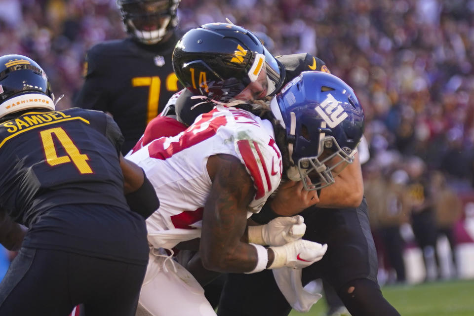 Washington Commanders quarterback Sam Howell (14) is hit by New York Giants safety Xavier McKinney (29) as he scores a touchdown during the first half of an NFL football game, Sunday, Nov. 19, 2023, in Landover, Md. Also on the field is Washington Commanders wide receiver Curtis Samuel (4). (AP Photo/Andrew Harnik)