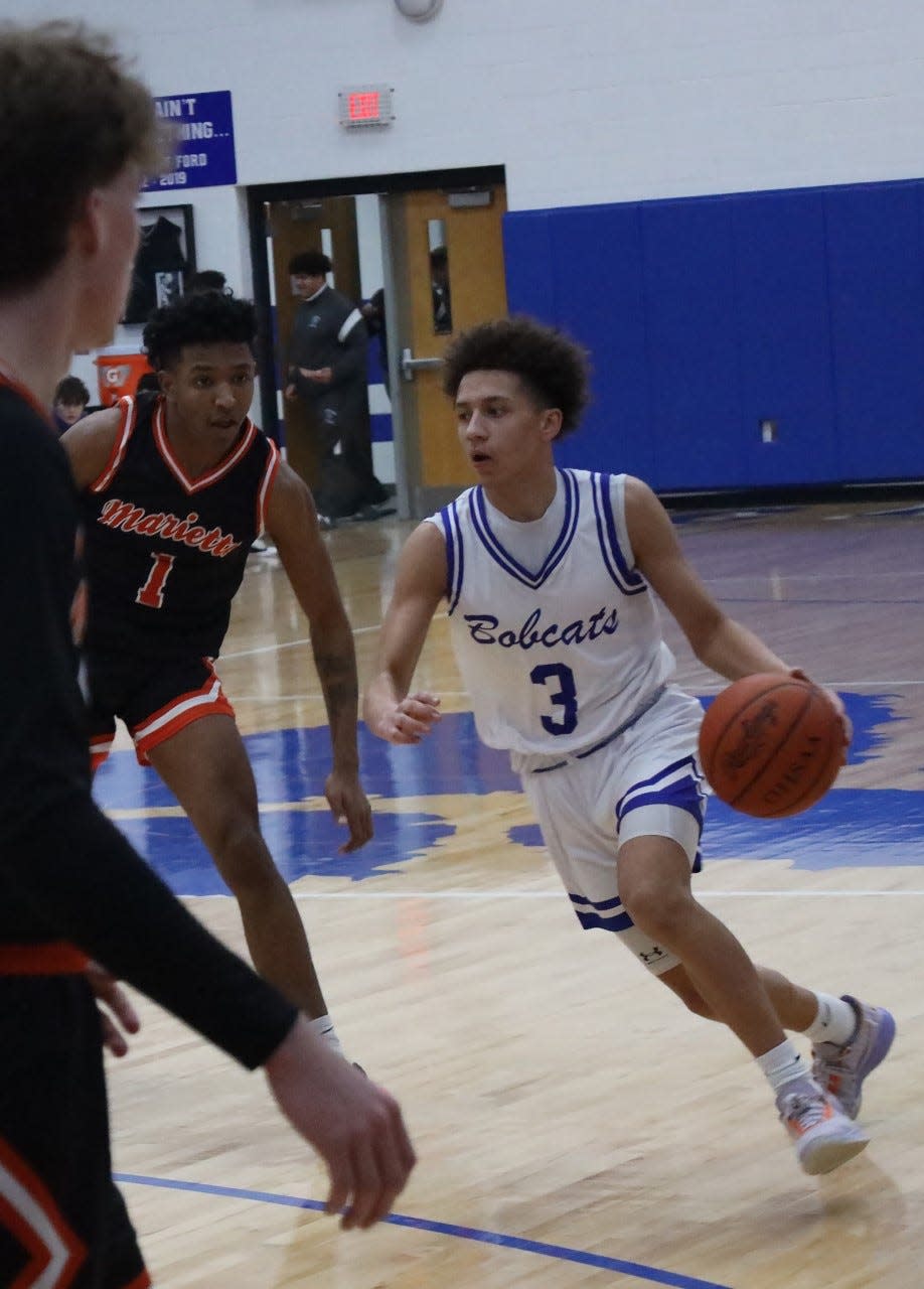 Cambridge sophomore Jesiah Barnett (3) maneuvers around Marietta's Elyjah Lieras-Kelley (1) during Friday's game inside Gene Ford Gymnasium.