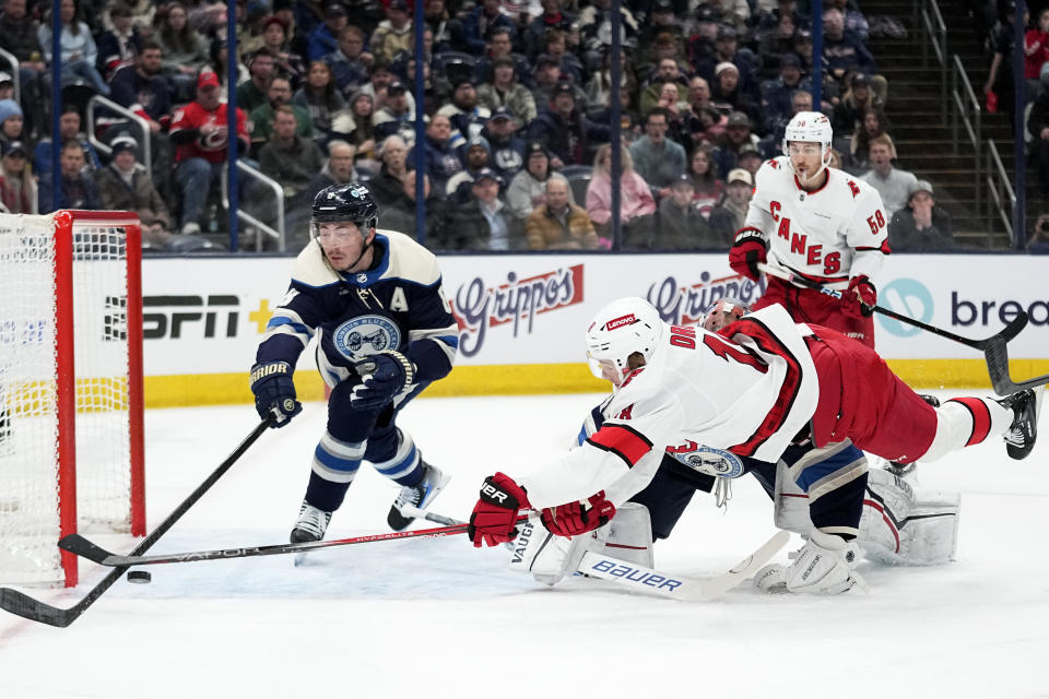 Carolina Hurricanes center Jack Drury, front right, tumbles over Columbus Blue Jackets goaltender Daniil Tarasov as Blue Jackets defenseman Zach Werenski, left, moves in to clear the puck in the first period of an NHL hockey game Thursday, Feb. 29, 2024, in Columbus, Ohio. (AP Photo/Sue Ogrocki)