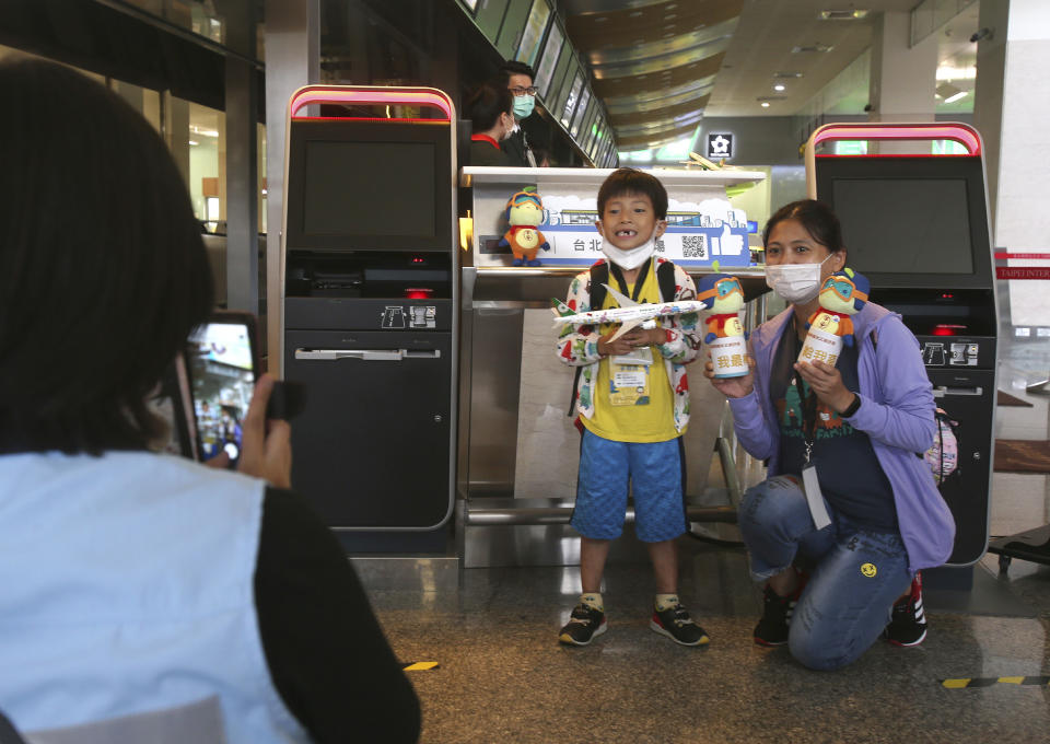 Participants take a photo with airline souvenirs during a mock trip abroad at Taipei Songshan Airport in Taipei, Taiwan, Tuesday, July 7, 2020. Dozens of would-be travelers acted as passengers in an activity organized by Taiwan’s Civil Aviation Administration to raise awareness of procedures to follow when passing through customs and boarding their plane at Taipei International Airport. (AP Photo/Chiang Ying-ying)