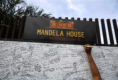 A mourner writes a message at the house of Nelson Mandela in Soweto at the outskirts of Johannesburg December 7, 2013.REUTERS/Yannis Behrakis