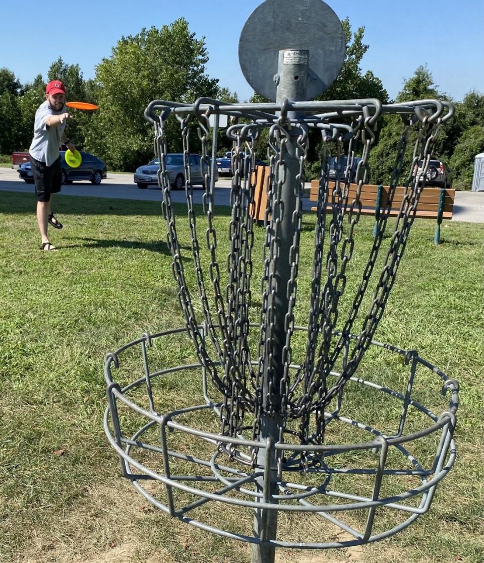 Disc golf features players tossing discs, or Frisbees, at a target with similar scoring rules as golf.