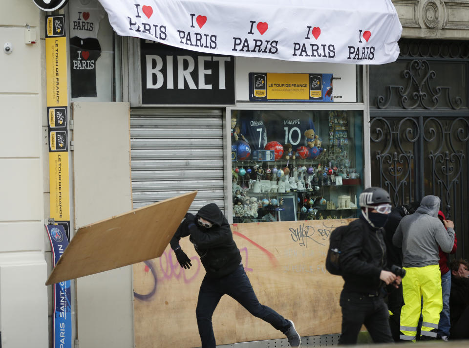 Youths vandalized a shop, Saturday, March 16, 2019 in Paris. French yellow vest protesters clashed Saturday with riot police near the Arc de Triomphe as they kicked off their 18th straight weekend of demonstrations against President Emmanuel Macron. (AP Photo/Christophe Ena)