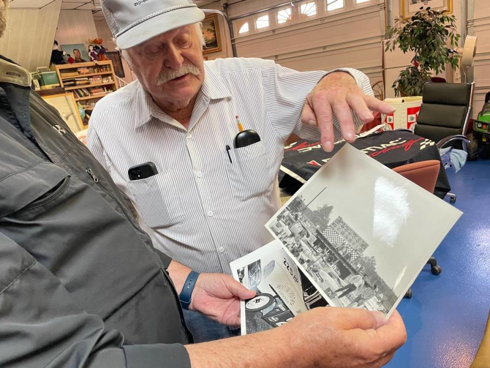 Ken Brooks, center, takes a look at a photo that Mike Staley has stashed away of the old scoreboard at North Wilkesboro Speedway ahead of the NASCAR All-Star Race on Sunday, May 21, 2023.