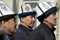 Protesters wearing Kyrgyz national hats listen to a speaker during a rally in front of the government building, in Bishkek, Kyrgyzstan, Wednesday, Oct. 14, 2020. Kyrgyzstan's embattled president has discussed his possible resignation with his newly appointed prime minister in a bid to end the political crisis in the Central Asian country after a disputed parliamentary election. President Sooronbai Jeenbekov held talks with Prime Minister Sadyr Zhaparov a day after refusing to appoint him to the post over concerns whether parliament could legitimately nominate him. (AP Photo/Vladimir Voronin)