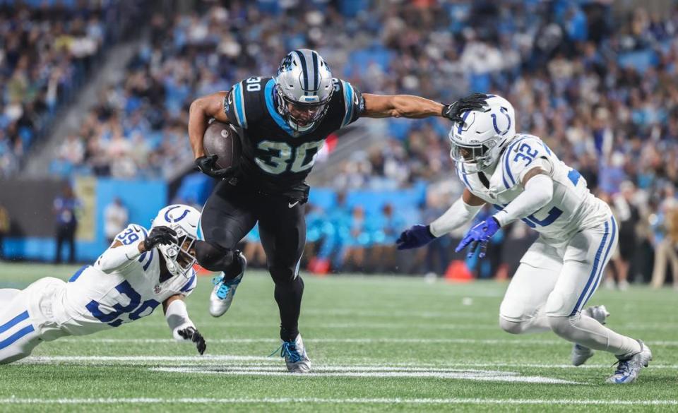 Carolina Panthers running back Chuba Hubbard, center, stiff arms Indianapolis Colts safety Julian Blackmon at the Bank of America Stadium in Charlotte, N.C., on Sunday, November 5, 2023.