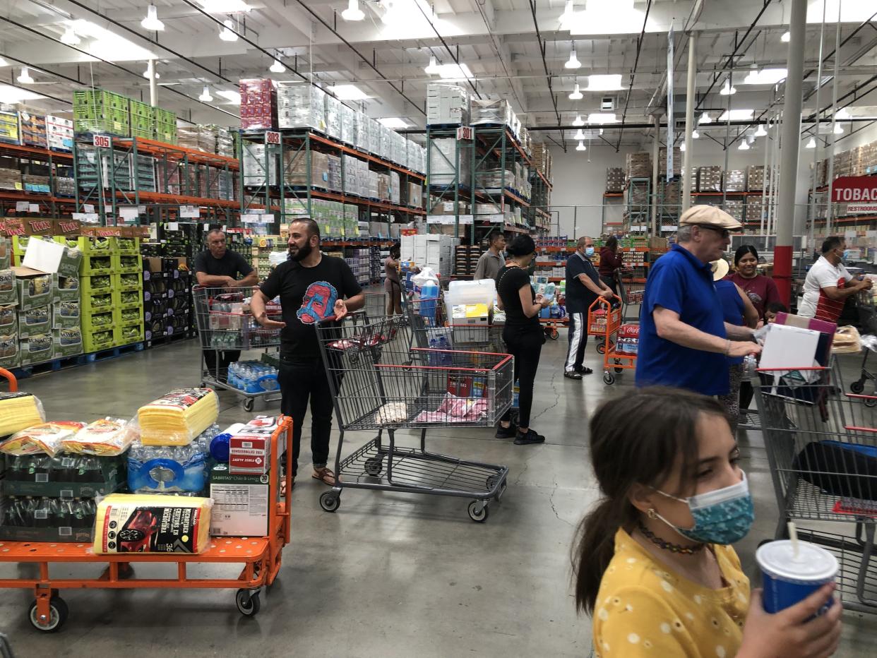 A few customers with orange carts are shown in line at a Costco Business Center