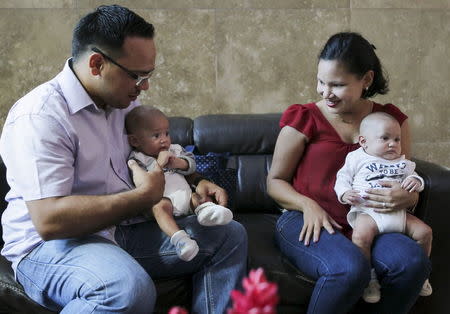 Patricia Fernandez (R), 27, and her husband, carry their twins during an interview with Reuters in Maracaibo, Venezuela June 17, 2015. REUTERS/Isaac Urrutia