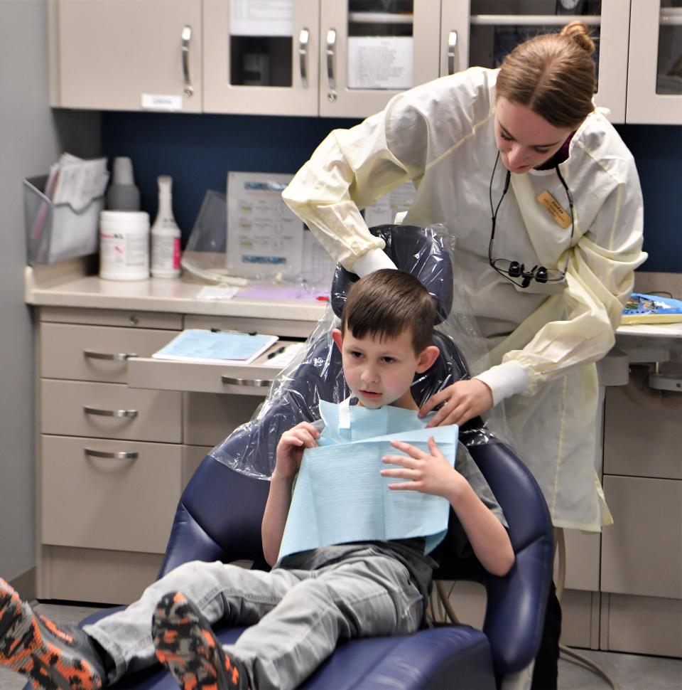 MSU Texas dental hygiene major Jordan Cochran ties a blue neck bib around her patient during MSU's "Give Kids A Smile Day" Monday, Feb. 20, 2023, at Centennial Hall.