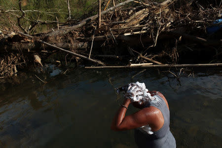 A local resident washes her hair at a pond after Hurricane Maria destroyed the town's bridge in San Lorenzo, Morovis, Puerto Rico, October 4, 2017. REUTERS/Alvin Baez