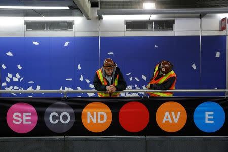 Workers Ryan Walker and Michael Grund peer over onto the platform at the 96th Street Station during a preview event for the Second Avenue subway line in Manhattan, New York City, U.S., December 22, 2016. REUTERS/Andrew Kelly