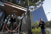 A security stands watch as an employee walks out from the Huawei research and development centre in Dongguan in south China's Guangdong province, Tuesday, Dec. 18, 2018. While a top executive of Chinese tech giant Huawei faces possible U.S. charges over trade with Iran, the company's goal to be a leader in next-generation telecoms is colliding with security worries abroad. Australia and New Zealand have barred Huawei as a supplier for fifth-generation networks, joining the U.S. and Taiwan. Last week, Japan's cybersecurity agency said Huawei and other vendors deemed risky will be off-limits for government purchases. (AP Photo/Andy Wong)