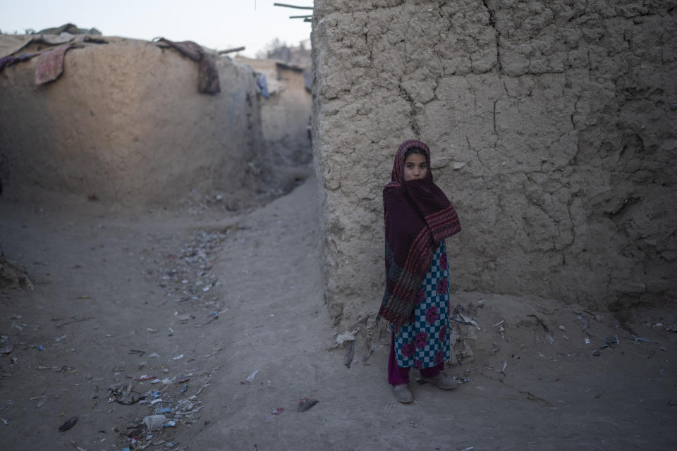 A girl stands outside a mud brick house at a camp for internally displaced people, in Kabul, Afghanistan, Monday, Nov. 15, 2021. (AP Photo/ Petros Giannakouris)