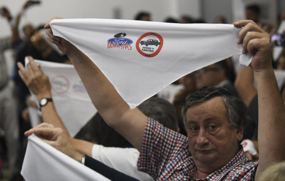 Family members of ex-Ford Motor Co. employees hold up handkerchiefs that are stamped with a message that reads in Spanish: “Ford never more” in a courtroom where former Ford Motor Co. executives, who are charged with crimes against humanity for allegedly targeting Argentine union workers for kidnapping and torture after the country's 1976 military coup, await sentencing in Buenos Aires, Argentina, Tuesday, Dec. 11, 2018. (AP Photo/Gustavo Garello)
