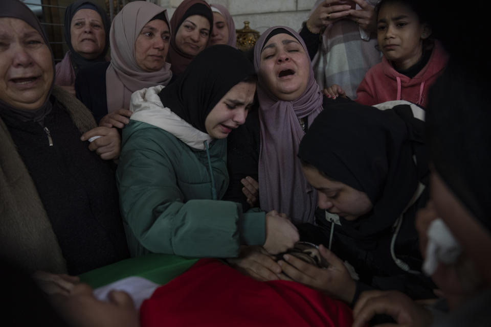 Huda Qatawi, center and family members cry while they take the last look at the body of her son Hazem Qatawi, 23 during his funeral in the West Bank city of Beitunia, Thursday, Dec. 28, 2023. Palestinian health ministry said that Qatawi was killed during an Israeli army raid in Ramallah early morning. (AP Photo/Nasser Nasser)