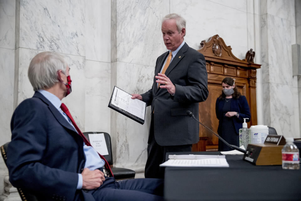 Chairman Sen. Ron Johnson, R-Wis., center, speaks with Sen. Rob Portman, R-Ohio, left, at the conclusion of a Senate Homeland Security and Governmental Affairs committee meeting on Capitol Hill in Washington, Wednesday, May 20, 2020, after voting to issue a subpoena to Blue Star Strategies. (AP Photo/Andrew Harnik)