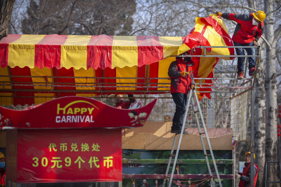 Workers dismantle a carnival built for a canceled Lunar New Year temple fair at Longtan Park in Beijing, Saturday, Jan. 25, 2020. China's most festive holiday began in the shadow of a worrying new virus Saturday as the death toll surpassed 40, an unprecedented lockdown kept 36 million people from traveling and authorities canceled a host of Lunar New Year events. (AP Photo/Mark Schiefelbein)