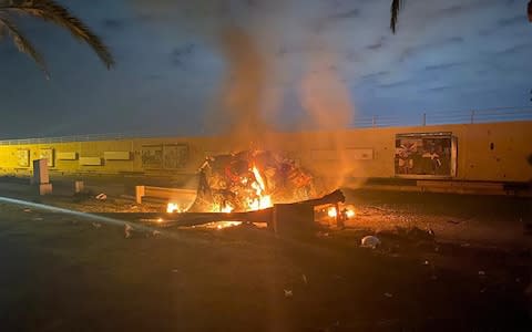 A destroyed vehicle on fire after a US strike at Baghdad international airport - Credit: AFP