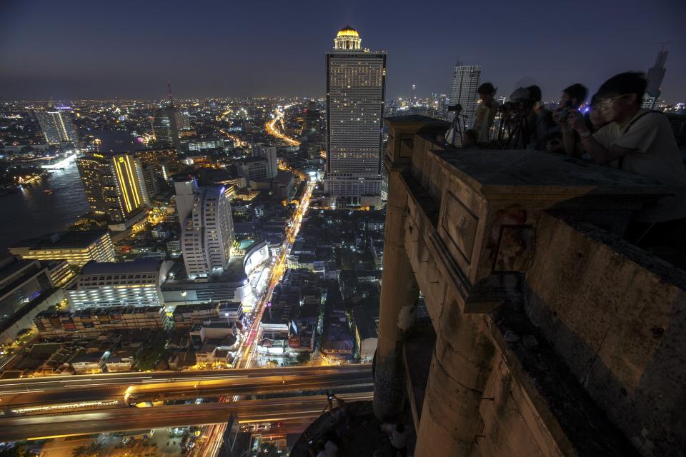 Visitors take photographs from a top of an abandoned skyscraper in Bangkok