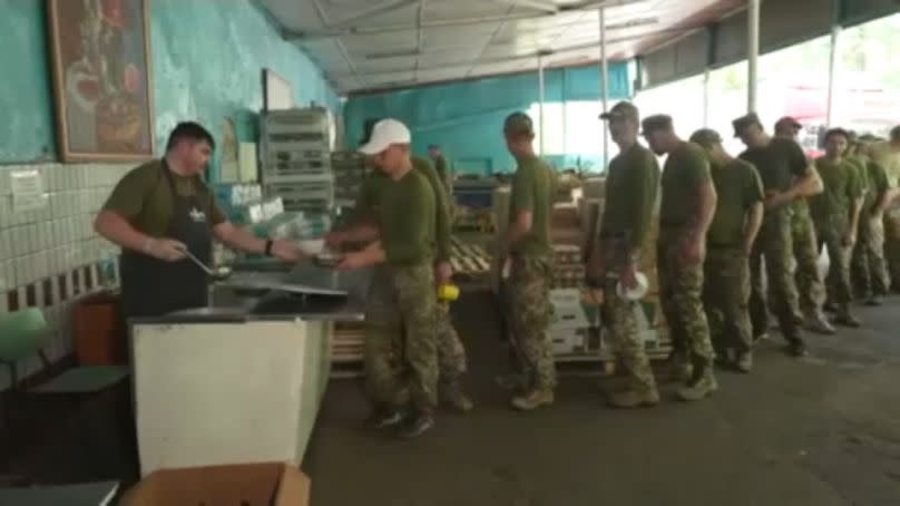 Ex-convicts line up for food at military training camp.