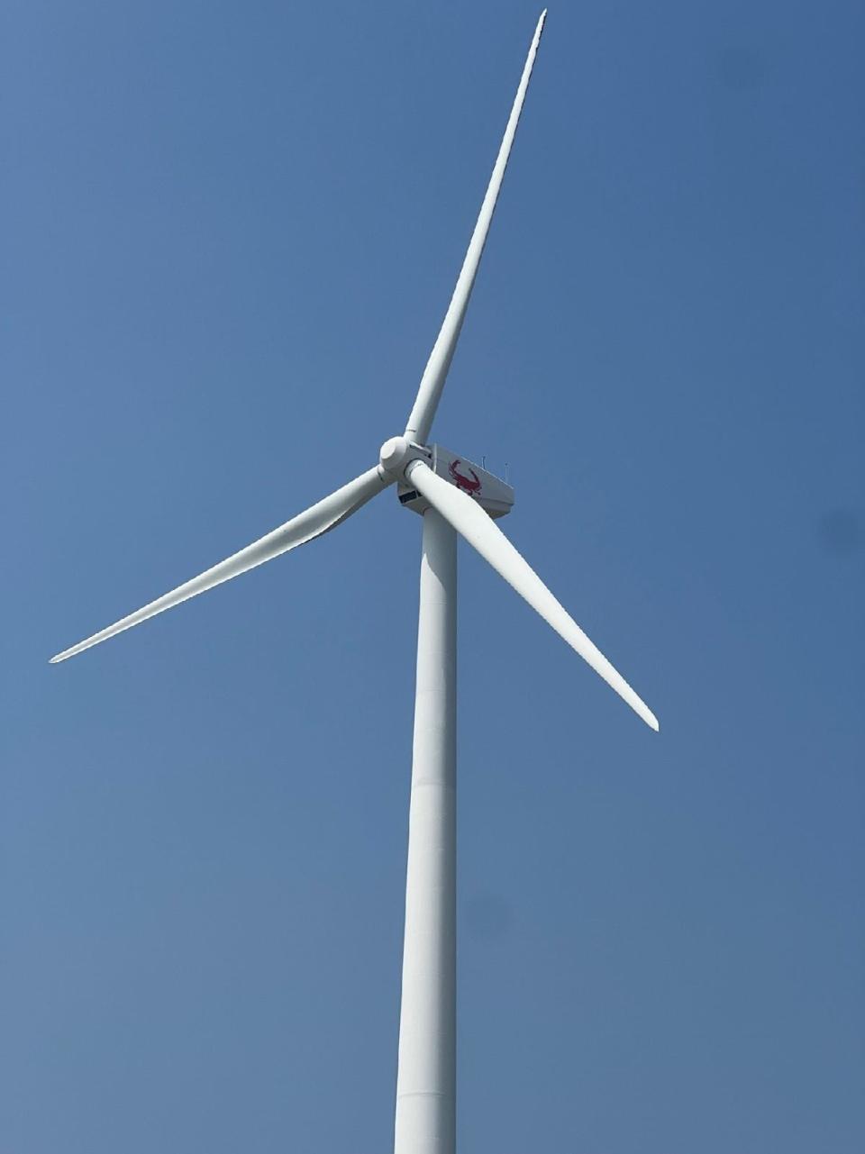 A wind turbine, which helps power the city of Crisfield's wastewater treatment plant, spins on June 29, 2023. An image of a crab is located near the 69-foot blades.