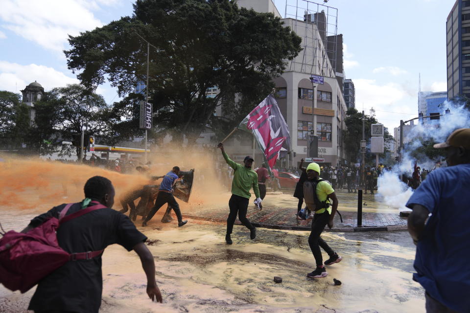 Protesters scatter as Kenya police spray water canon at them during a protest over proposed tax hikes in a finance bill in downtown Nairobi, Kenya Tuesday, June. 25, 2024. (AP Photo/Brian Inganga)