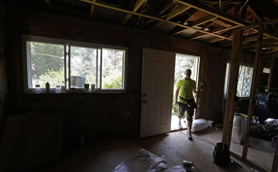 FILE - Homeowner Jennifer Baker walks through the front door of her home damaged by Hurricane Florence in 2018 while repairs continue in Spring Lake, N.C., Tuesday, July 2, 2019. Nearly six years after extreme rainfall and flooding from Hurricane Matthew damaged many North Carolina homes, some homeowners are still left waiting on repairs. A new bipartisan General Assembly committee tasked with investigating the delays holds its first meeting Wednesday, Sept. 14, 2022, on the four-year anniversary of when Hurricane Florence made landfall in North Carolina. (AP Photo/Gerry Broome, File)