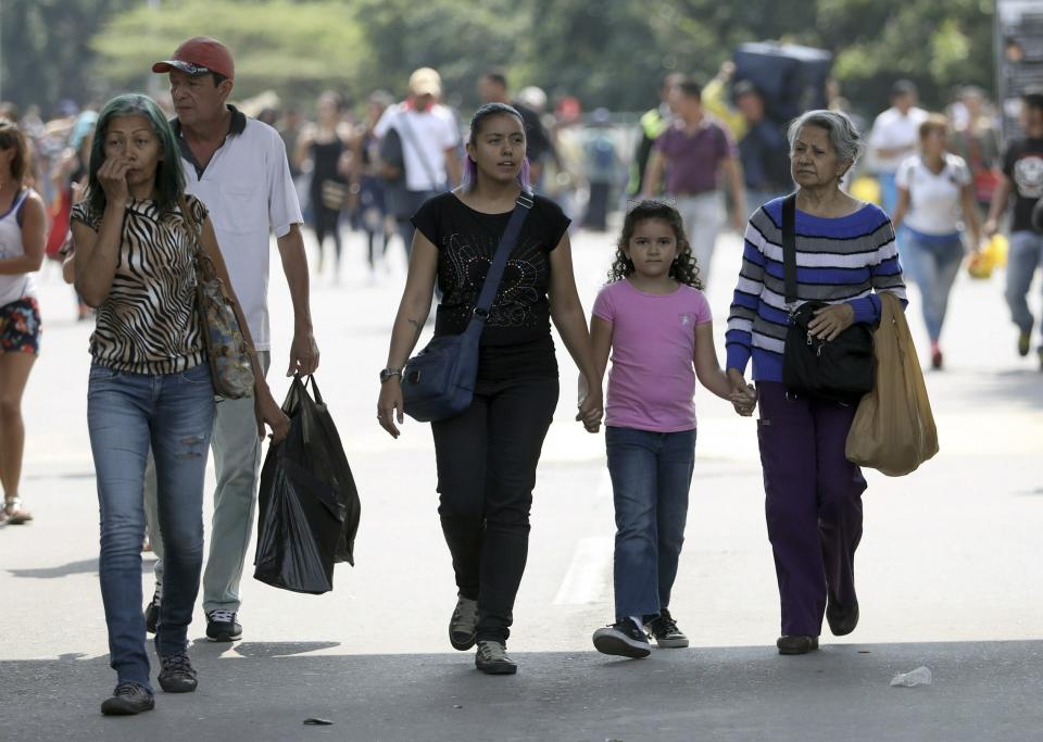 In this Feb. 11, 2019 photo, Venezuelan Diomira Becerra, left center, arrives with her 7-year-old daughter Hillary and her mother Betty Guerrero, for an interview at the entrance of the Simon Bolivar International Bridge, in La Parada, Colombia, near Cucuta. Becerra left Venezuela three years ago and has built a life for her family in the border city of Cucuta. (AP Photo/Fernando Vergara)