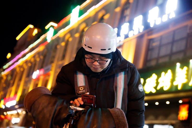 Liu Pengfei, a substitute driver of DiDi Chuxing, checks the ride-hailing app before starting his night shift in Beijing