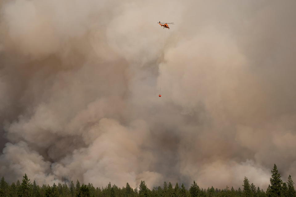 A helicopter flies in a smoke filled sky on the Chuweah Creek Fire as wildfires devastate Nespelem in eastern Washington state.