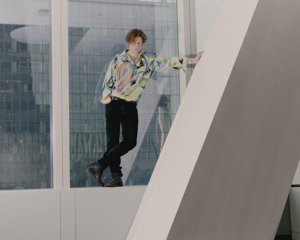 Matt Smith posing for a portrait standing on an office space windowsill.