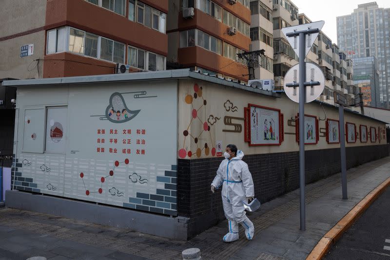 An epidemic prevention worker in a protective suit walks in a street as outbreaks of the coronavirus disease (COVID-19) continue in Beijing