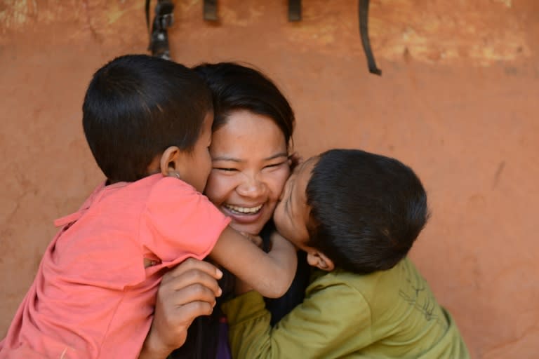 Nepalese migrant worker Sunita Magar (C), who was trafficked to Syria, is being hugged by her children, son Bipin Magar (R) and daughter Elina Magar, at their home in Dhadhing district, some 100 km west of Kathmandu