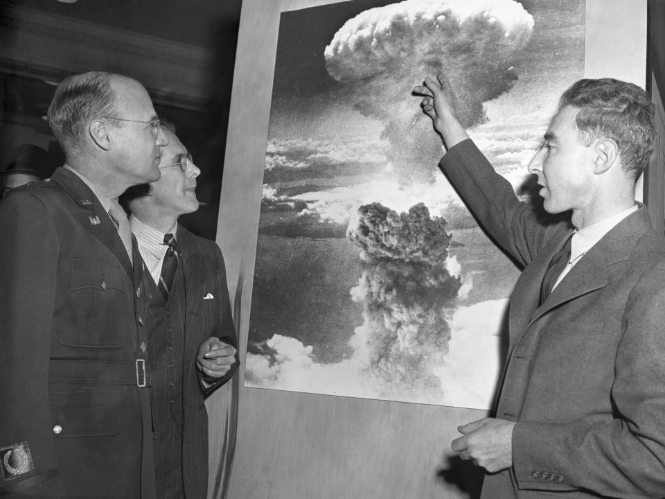 J. Robert Oppenheimer looking at a photo of the atomic bomb dropped on Nagasaki with two officials in 1946.