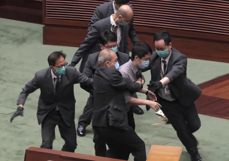 Pro-democracy lawmaker Ted Hui, center, struggles with security personnel at the main chamber of the Legislative Council during the second day of debate on a bill that would criminalize insulting or abusing the Chinese anthem in Hong Kong, Thursday, May 28, 2020. A longer suspension followed the ejection of Ted Hui, who kicked the plastic bottle toward the president's dais after security officers tussled with him and it fell from his hands. (AP Photo)