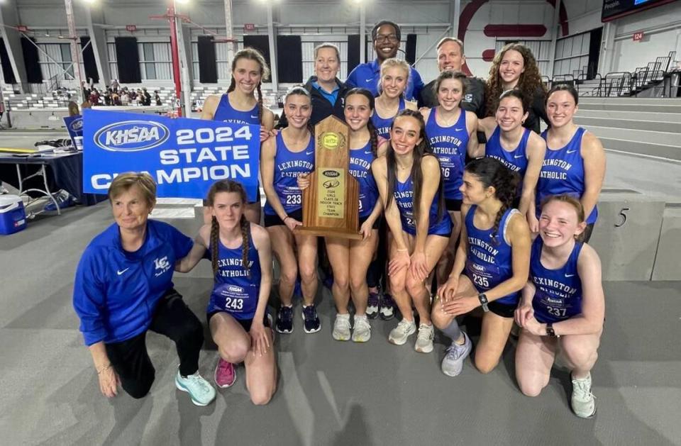 Lexington Catholic’s girls indoor track team, coached by Bernadette Madigan-Dugan, left, posed with their state championship trophy after winning the inaugural Class 2A KHSAA Indoor Track & Field State Championships at Norton Healthcare Sports & Learning Center in Louisville on Saturday.