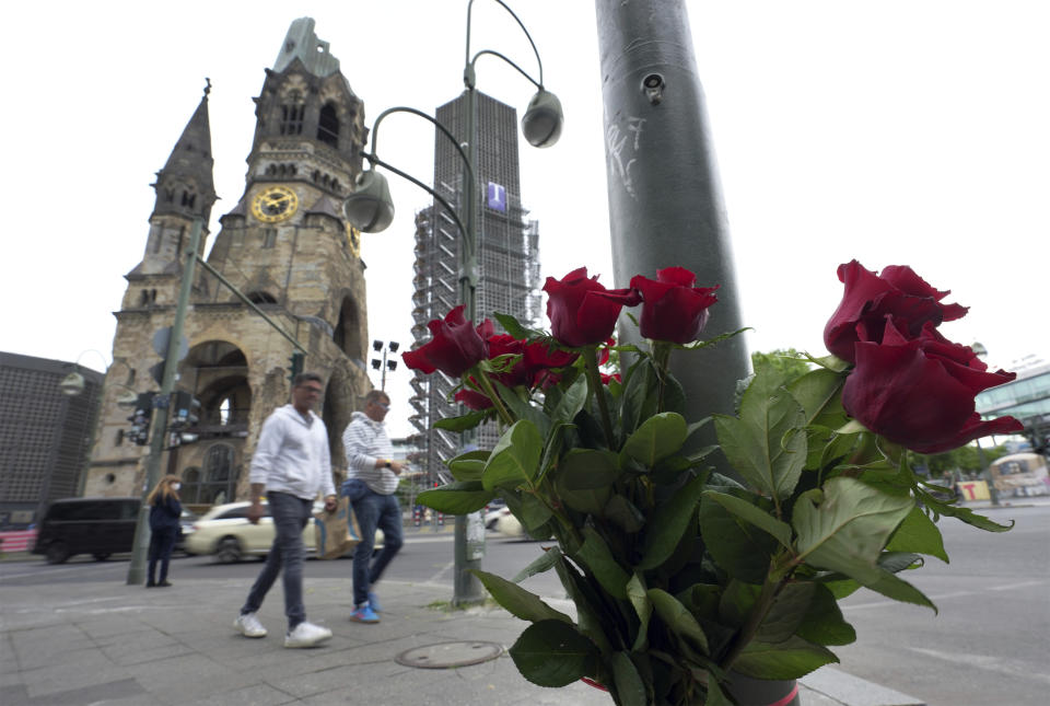 People walk past flowers at the Kaiser Wilhelm Memorial Church in Berlin, Germany, Thursday, June 9, 2022. On Wednesday June 8, a 29-year-old man drove his car into a group of students killing their teacher and crash into a store. (AP Photo/Michael Sohn)