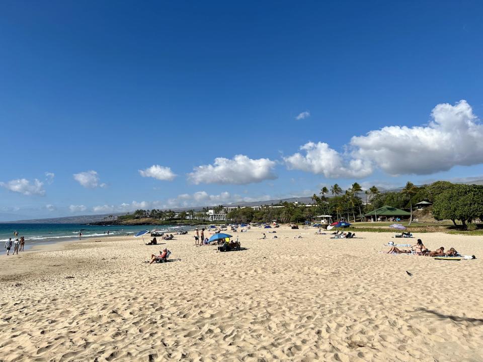 A view of the south end of Hapuna Beach, with lots of sand, water, and beachgoers