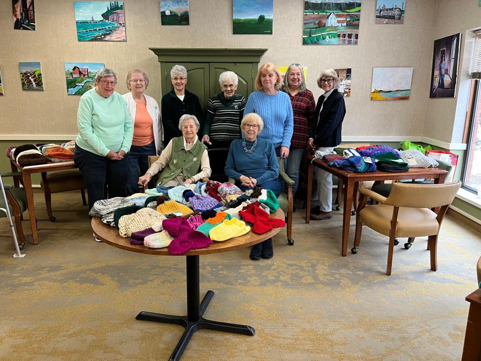Several members of the Independence Village Knitting Group pose with part of their donation of knitted hats and scarves on Thursday, Nov. 17, 2022, in Independence Village of East Lansing.
