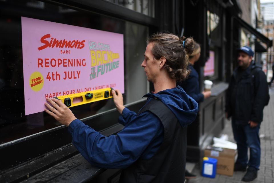 A man works to affix a sign advertising the planned July 4 re-opening of a bar in Soho in London on June 30, 2020, as coronavirus lockdown measures continue to be eased. - Pubs and restaurants will on July 4 be allowed to reopen, as will hotels, bed and breakfasts, self-catering accommodation and campsites, alongside cinemas, museums and galleries. (Photo by DANIEL LEAL-OLIVAS / AFP) (Photo by DANIEL LEAL-OLIVAS/AFP via Getty Images)