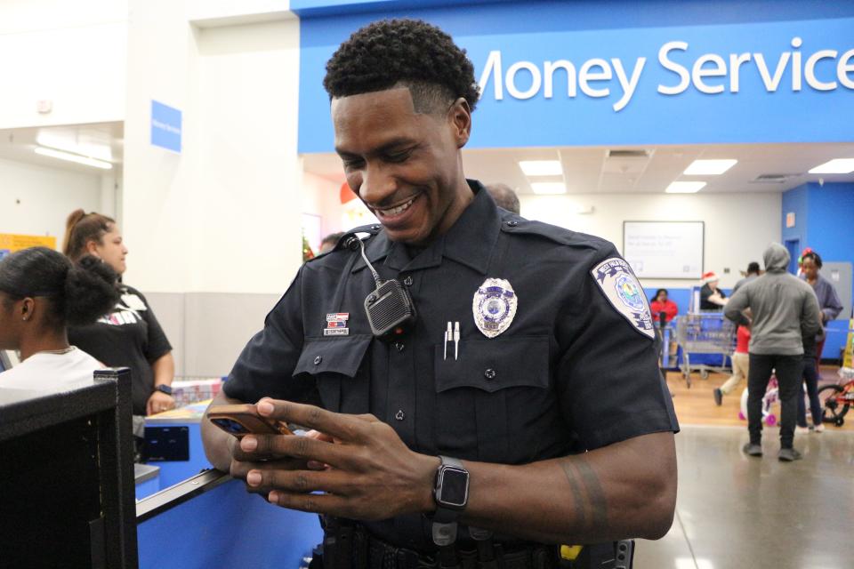 Demetrius Latham Jr., a West Palm Beach Police Officer, smiles as he oversees the department's Shop with a Cop event on Dec. 7, 2022.