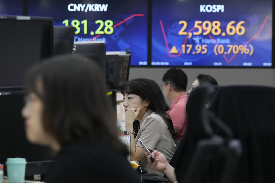 A currency trader watches monitors near the screens showing the Korea Composite Stock Price Index (KOSPI), right top, at the foreign exchange dealing room of the KEB Hana Bank headquarters in Seoul, South Korea, Tuesday, Aug. 8, 2023. Asian stocks were mixed Tuesday after Wall Street rallied and Japanese wages rose ahead of a U.S. inflation update that might influence Federal Reserve plans for more possible interest rate hikes. (AP Photo/Ahn Young-joon)